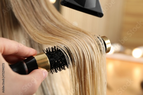 Hairdresser blow drying client's hair in salon, closeup