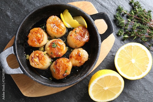 Delicious fried scallops and ingredients on dark gray textured table, flat lay