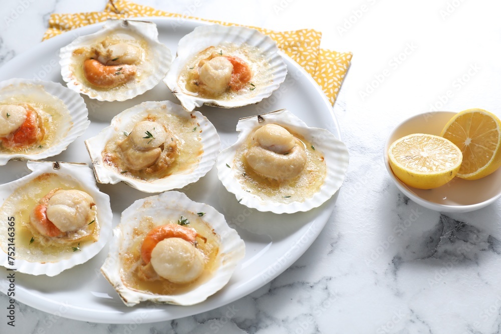 Fried scallops in shells and lemon on white marble table Fried scallops in shells and lemon on white marble table