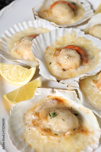Fried scallops in shells and lemon on plate, closeup