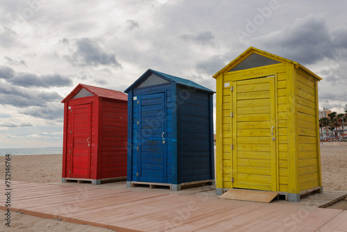 Casetas de madera de colores en la playa de Villajoyosa a contraluz en día nublado, España