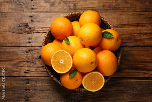 Many ripe oranges and green leaves on wooden table, top view