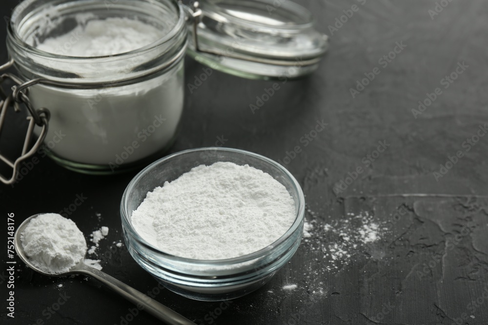 Baking powder in bowl, jar and spoon on black textured table, closeup. Space for text Baking powder in bowl, jar and spoon on black textured table, closeup. Space for text