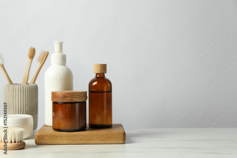 Different bath accessories and personal care products on light marble table against white wall, space for text Different bath accessories and personal care products on light marble table against white wall, space for text