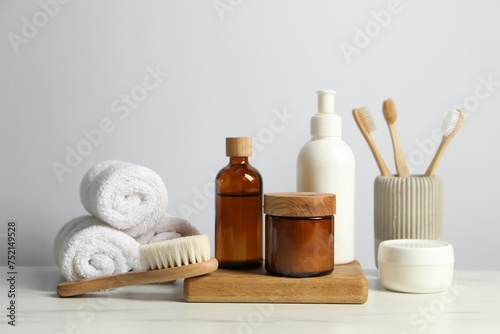 Different bath accessories and personal care products on light marble table against white wall