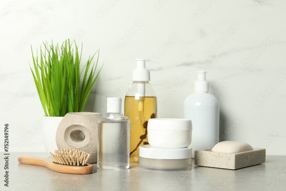 Brush and personal care products on gray table near white marble wall Brush and personal care products on gray table near white marble wall