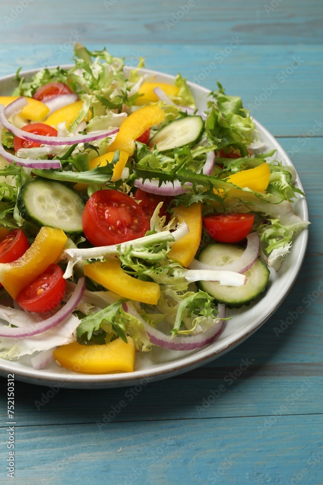 Tasty fresh vegetarian salad on light blue wooden table, closeup
