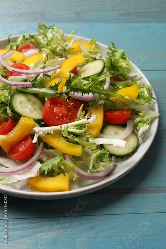 Tasty fresh vegetarian salad on light blue wooden table, closeup
