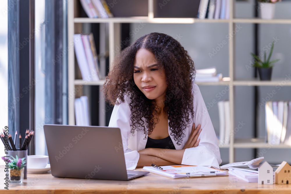 Businesswomen are stressed with work in front of a laptop and paper documents in the office. Businesswomen are stressed with work in front of a laptop and paper documents in the office.