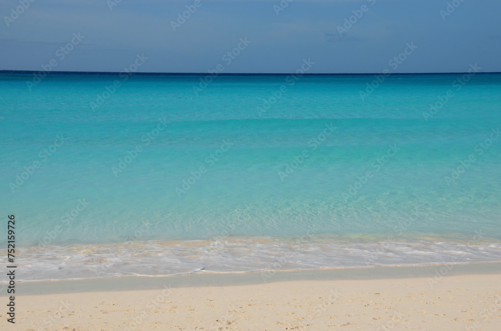 Tropical beach landscape, soft turquoise sea, clear sandy beach, blue sky