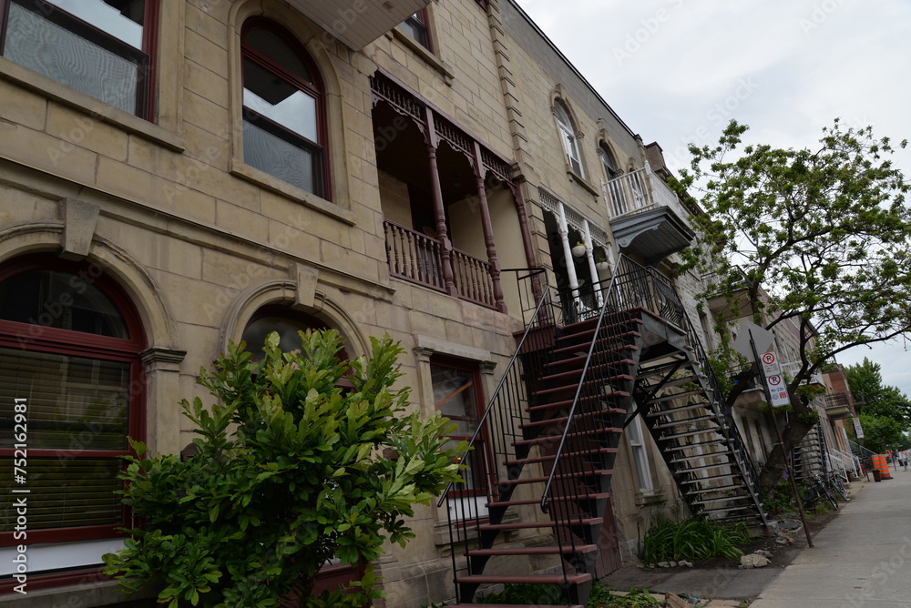 Multiple fire escape staircases ascending alongside a building on a narrow sidewalk