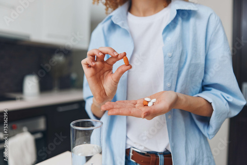 Obraz na plátně Woman holding pill standing in front of glass water preparing take medication he