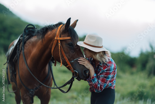 Happy blonde with horse in forest. Woman and a horse walking through the field during the day. Dressed in a plaid shirt and black leggings. © svetograph