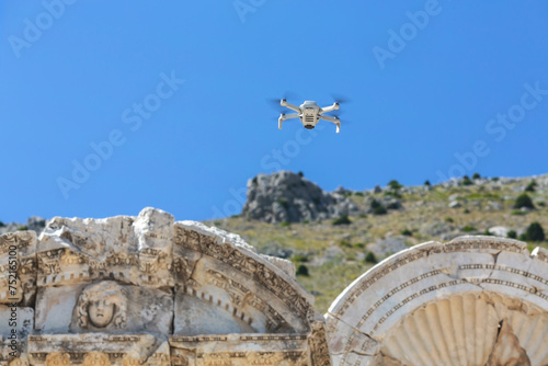 Drone hovers over Sagalassos ruins, capturing photos, ancient carved stones, clear sky, mountain backdrop. Aglasun, Burdur, Turkey (Turkiye) photo