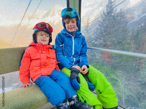 Siblings skiers enjoy ski lift ride together in mountain resort