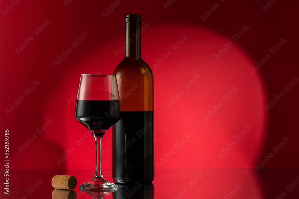 Bottle of red wine with wine glass and cork on table. View with space for your text.
