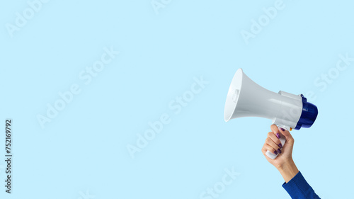 Megaphone in woman hand on blue background. Creative announcement concept.