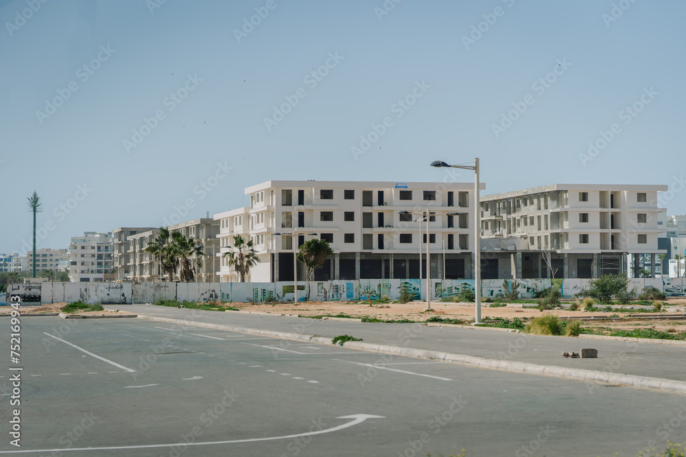 Agadir, Morocco - February 25, 2024 - New apartment buildings under construction in a developing area with sparse vegetation and clear skies.