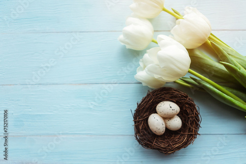 Quail eggs in the nest and tulips, top view. Easter concept