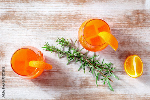 Orange cocktails with rosemary, overhead flat lay shot on a wooden background