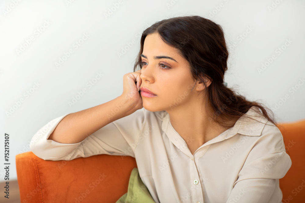 Portrait Of Pensive Upset Young Woman Sitting On Couch At Home Portrait Of Pensive Upset Young Woman Sitting On Couch At Home