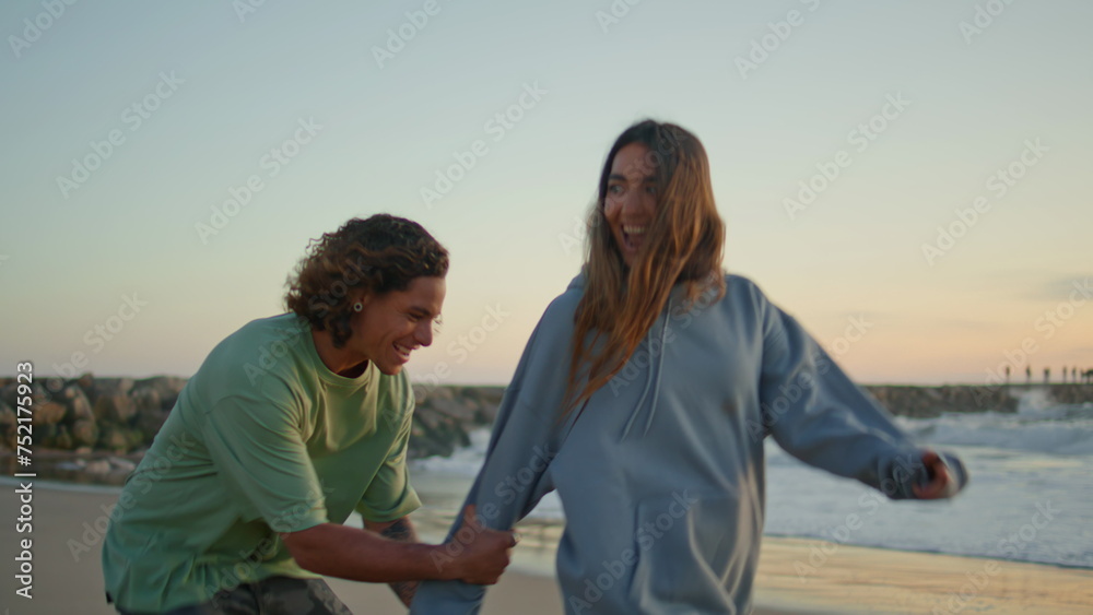 Carefree lovers having fun at sunset beach. Love couple embracing at sea coast Carefree lovers having fun at sunset beach. Love couple embracing at sea coast