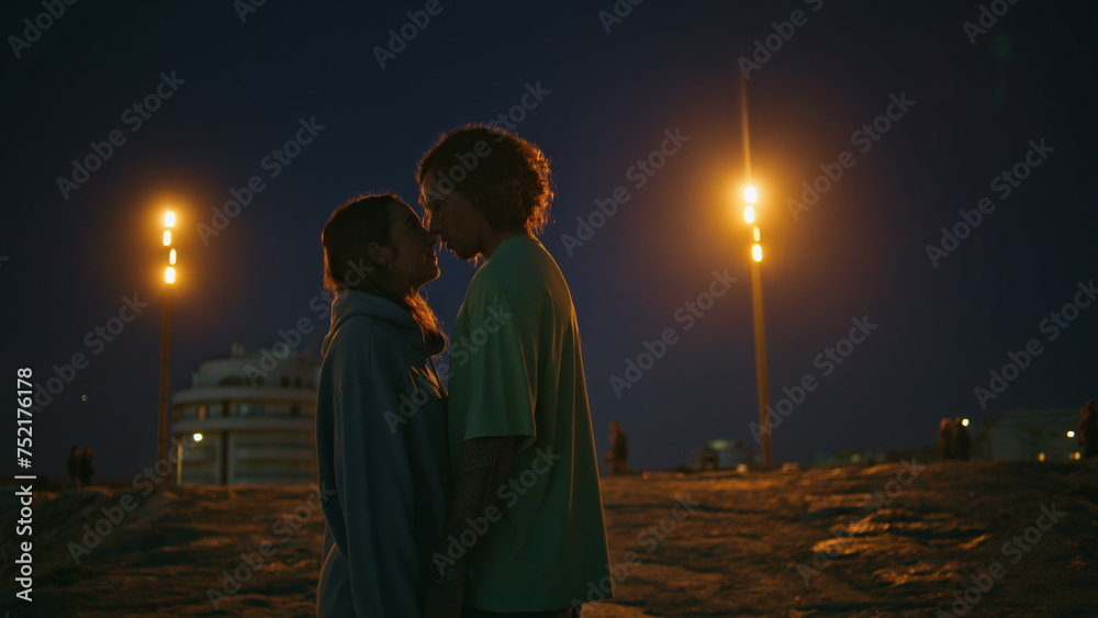 Loving teenagers looking eyes to eyes at night beach. Romantic couple dating