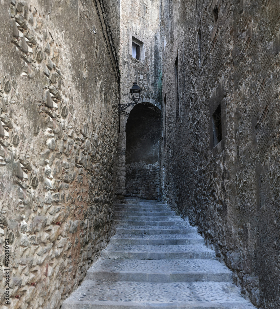 Scenic view of stone steps leading up to an arch in a narrow alleyway