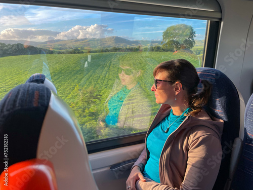 Young lady sits by window on a train and admires beautiful Yorkshire landscape