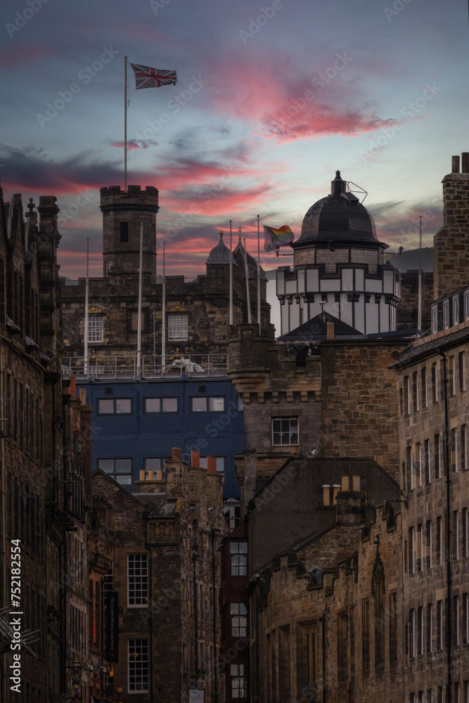 Pink clouds roll over old city street with stone buildings and Edinburgh Castle