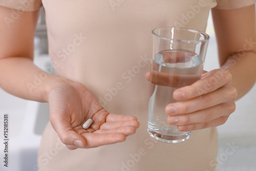 Beautiful young woman with vitamin pill and glass of water, closeup © New Africa