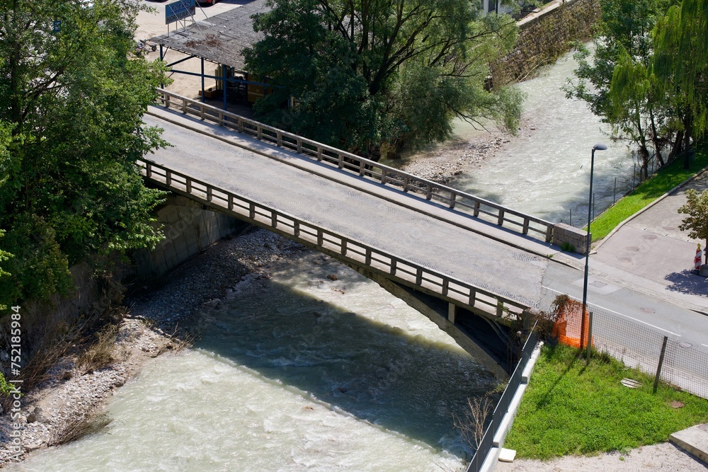 Fototapeta premium Aerial view of bridge over Kokra River seen from viewpoint platform at the old town of Kranj on a sunny summer day. Photo taken August 10th, 2023, Kranj, Slovenia.