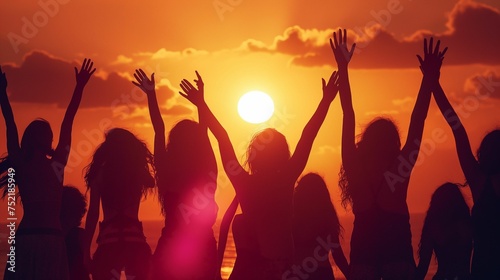 Silhouettes of many women with their hands raised in the background of the sunset.