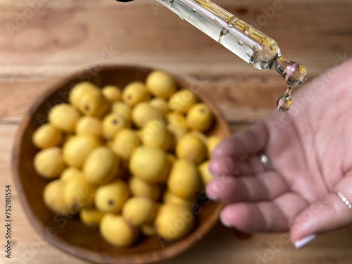Marula fruit cosmetic oil in a dropper with marula fruit in soft focus