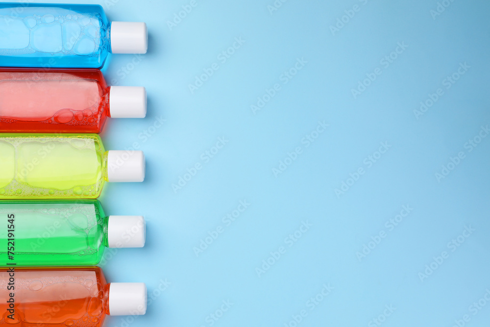 Fresh mouthwashes in bottles on light blue background, flat lay. Space for text Fresh mouthwashes in bottles on light blue background, flat lay. Space for text