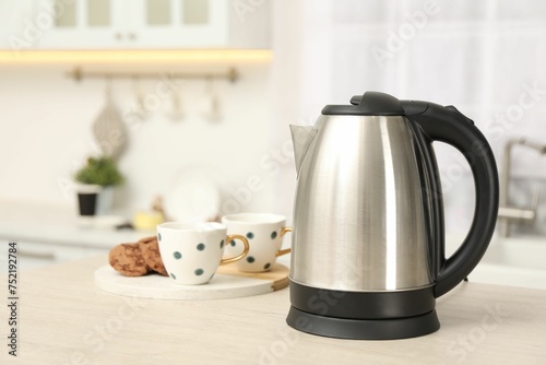 Modern electric kettle on table in kitchen. Space for text photo