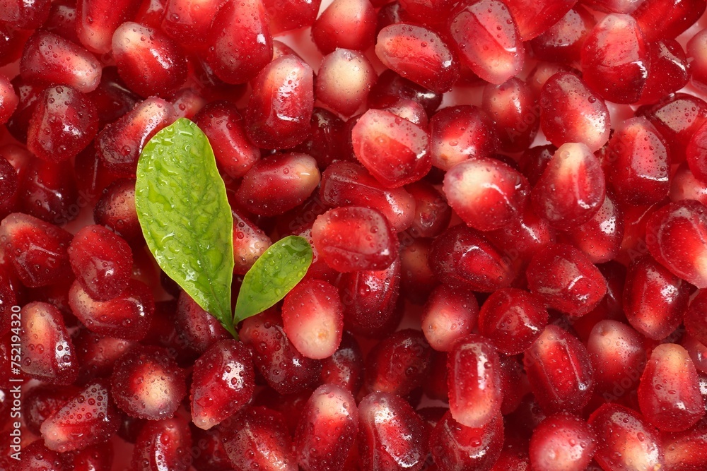 Green leaves on ripe juicy pomegranate grains, top view Green leaves on ripe juicy pomegranate grains, top view