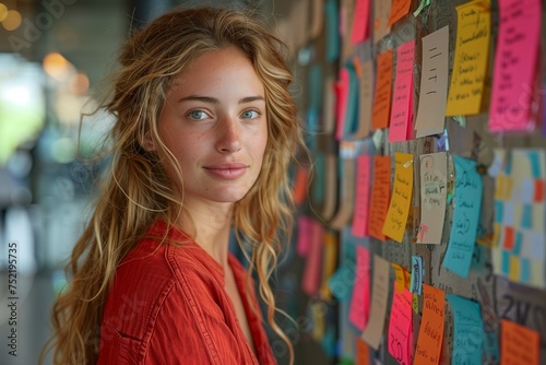 Thoughtful Professional in Red Shirt Engages with Wall of Brainstorming Sticky Notes