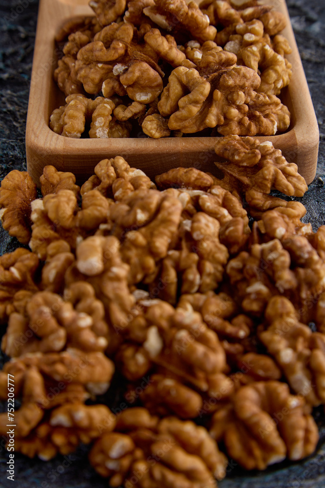 Top view of the halves of walnut kernels in a wooden plate on a gray background. Large walnuts in a wooden cup on a textured background Top view of the halves of walnut kernels in a wooden plate on a gray background. Large walnuts in a wooden cup on a textured background