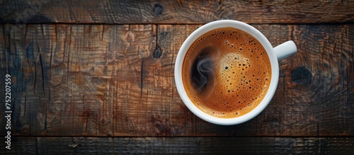 A cup of freshly brewed black coffee emitting steam, resting on a rustic wooden table.
