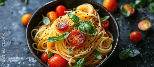 A bowl filled with al dente spaghetti pasta, topped with fresh tomatoes and basil leaves.