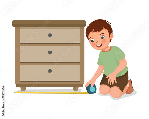Cute little boy measuring width of furniture with tape