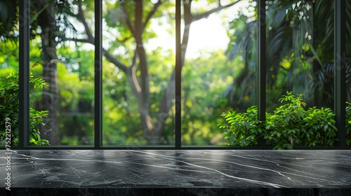 Empty black marble stone table top on blurred abstract green in sunlight.