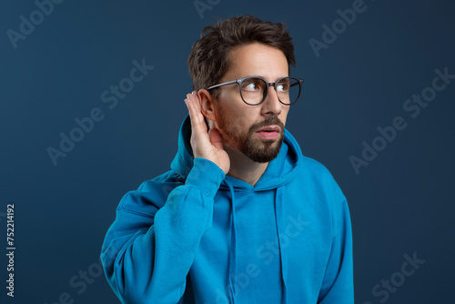 Curious Young Man Holding Hand Near Ear Trying To Overhear Something