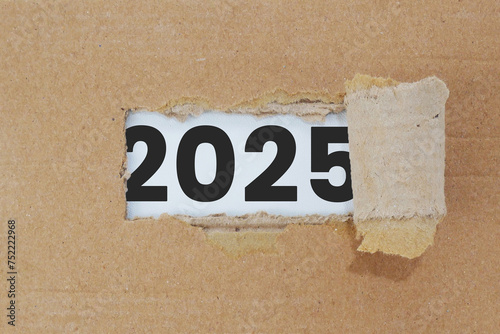 2025 behind torn cardboard. Happy new year 2025.