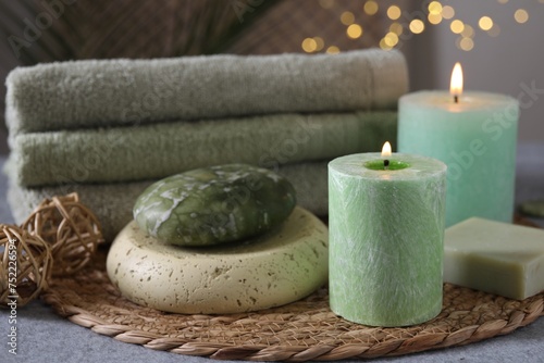 Spa composition. Burning candles, stone, soap and towels on grey table