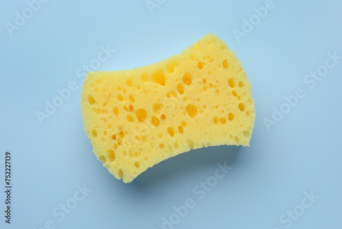 New yellow sponge on light blue background, top view