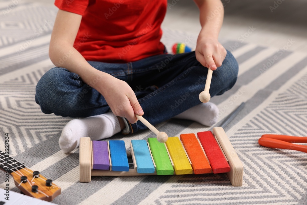 Little boy playing toy xylophone at home, closeup