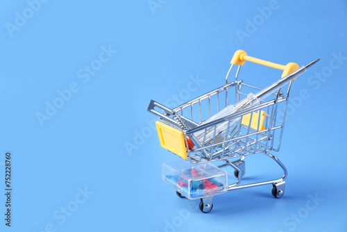 Small shopping cart with set of construction tools on light blue background. Space for text