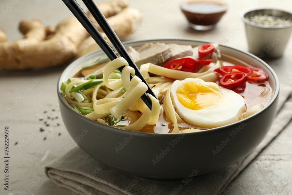 Eating delicious ramen with chopsticks at light table, closeup. Noodle soup Eating delicious ramen with chopsticks at light table, closeup. Noodle soup